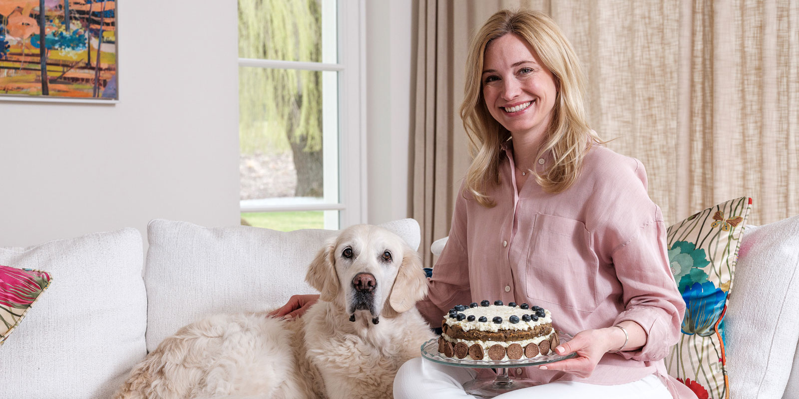 Katharina Miklauz sitzt mit Ihrer Hündin Nala auf der Bank und hält den gebackenen Kuchen in der Hand