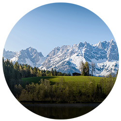 Landscape with green meadow, trees and mountains in the background