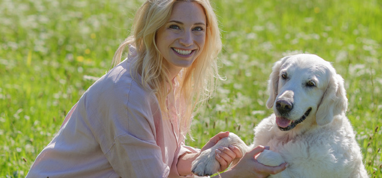 Katharina Miklauz sitzt mit ihrer Hündin Nala auf der Wiese